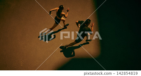 Competitive running partners race across a sunlit city pavement with focused energy Competitive running partners race across a sunlit city pavement with focused energy 142854819