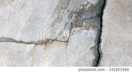 Damaged gray concrete wall with deep structural cracks. 142855498