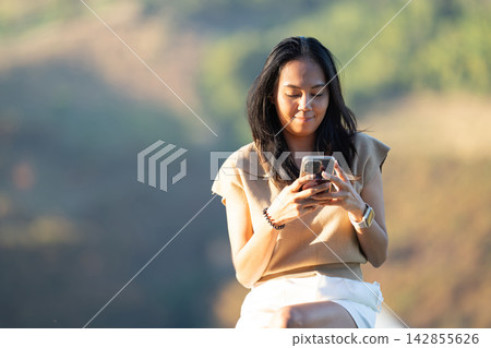 Asian woman interacting with her mobile smartphone device. Asian woman interacting with her mobile smartphone device. 142855626