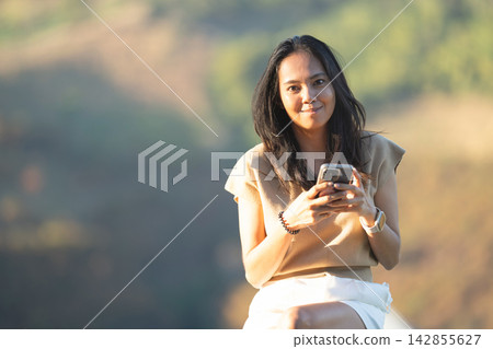 Asian woman interacting with her mobile smartphone device. Asian woman interacting with her mobile smartphone device. 142855627