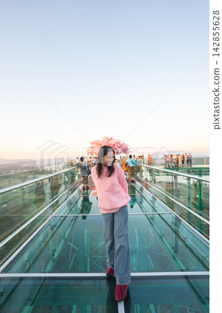 Asian female tourist walking on the transparent glass skywalk at Wat Phra That Pha Ngao in Chiang Rai. 142855628