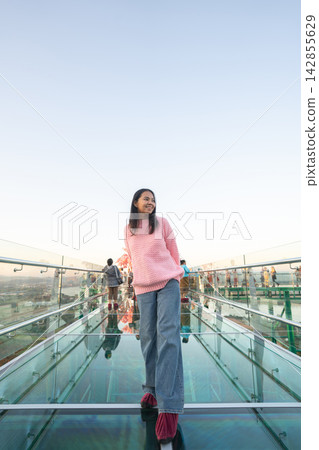 Asian female tourist walking on the transparent glass skywalk at Wat Phra That Pha Ngao in Chiang Rai. Asian female tourist walking on the transparent glass skywalk at Wat Phra That Pha Ngao in Chiang Rai. 142855629