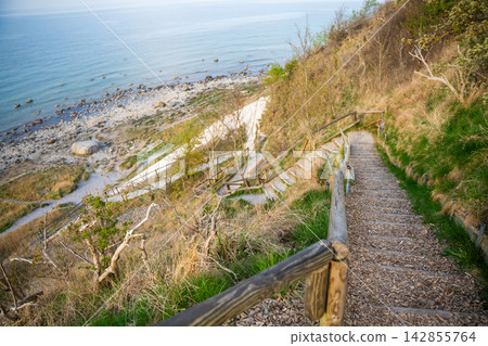 Wooden staircase leading to Baltic Sea beach near Cape Arkona on Rugen island in Germany. Coastal hiking and nature exploration atmosphere. 142855764