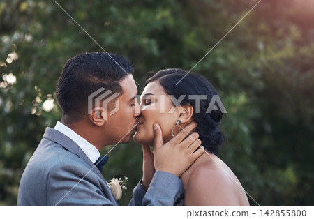Happy, couple and kiss on wedding day as celebration for love, commitment and success on marriage. Ceremony, woman and man at event as engagement reception together, support and care in sunshine 142855800