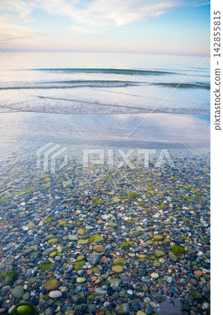 Transparent sea water with colorful stones on Ruegen island beach in Germany. Nature, coastline and clean Baltic Sea environment Transparent sea water with colorful stones on Ruegen island beach in Germany. Nature, coastline and clean Baltic Sea environment 142855815
