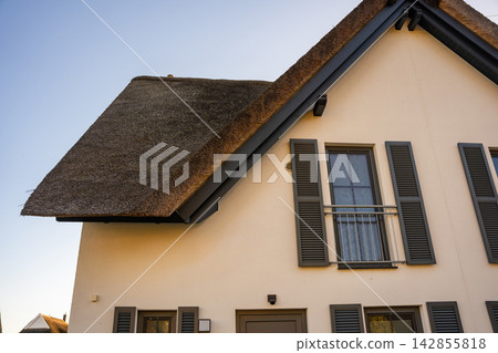 Traditional house with reed roof on Ruegen island in Germany. Coastal architecture and local building traditions near the Baltic Sea Traditional house with reed roof on Ruegen island in Germany. Coastal architecture and local building traditions near the Baltic Sea 142855818