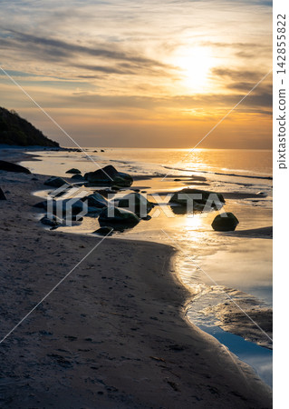 Rocky beach coastline on Ruegen island in Germany during sunset over the Baltic Sea. Travel, nature and seaside landscape with calm evening atmosphere Rocky beach coastline on Ruegen island in Germany during sunset over the Baltic Sea. Travel, nature and seaside landscape with calm evening atmosphere 142855822
