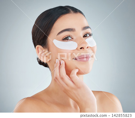 Studio, beauty and woman face with eye patch for dermatology, skin wellness and facial glow cosmetics. Skincare, female person and eyes with mask for dark circles and spa aesthetic by grey background Studio, beauty and woman face with eye patch for dermatology, skin wellness and facial glow cosmetics. Skincare, female person and eyes with mask for dark circles and spa aesthetic by grey background 142855823