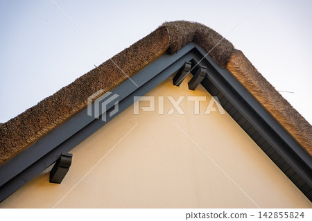 Traditional house with reed roof on Ruegen island in Germany. Coastal architecture and local building traditions near the Baltic Sea Traditional house with reed roof on Ruegen island in Germany. Coastal architecture and local building traditions near the Baltic Sea 142855824