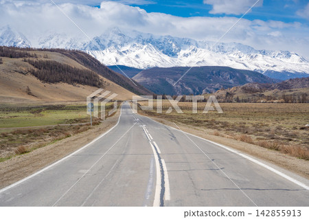 Asphalt road leading to snow-covered Akturu ridge in Kurai steppe valley Altai, Russia Asphalt road leading to snow-covered Akturu ridge in Kurai steppe valley Altai, Russia 142855913