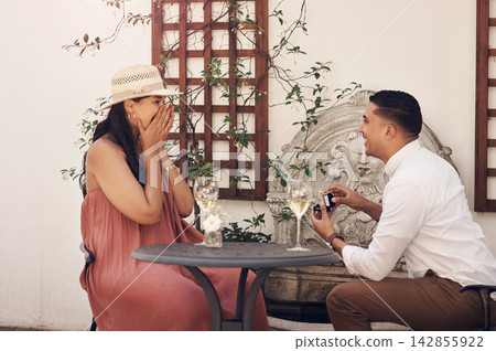 Happy, couple and date for surprise proposal with wedding ring at dinner, engagement and diamond for love of commitment. Surprised, woman and man for congratulations, jewellery and romance summer Happy, couple and date for surprise proposal with wedding ring at dinner, engagement and diamond for love of commitment. Surprised, woman and man for congratulations, jewellery and romance summer 142855922