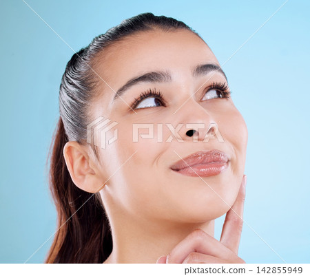Skincare, smile and woman with thinking in studio for dermatology, treatment and idea for self care. Happy, female person and face with shine for cosmetics, glow and satisfaction on blue background Skincare, smile and woman with thinking in studio for dermatology, treatment and idea for self care. Happy, female person and face with shine for cosmetics, glow and satisfaction on blue background 142855949