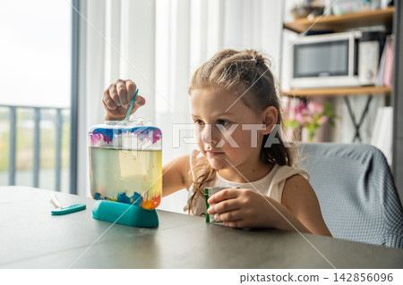 Little girl feeding artemia in aquarium by adding food into water. Learning through hands on activity and early education about care and simple biology processes. Little girl feeding artemia in aquarium by adding food into water. Learning through hands on activity and early education about care and simple biology processes. 142856096
