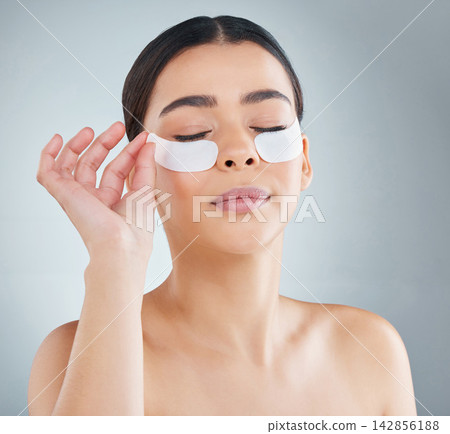 Woman, eye patch and hand in studio for skincare, dermatology and collagen or revitalise product for dark circles. Grey background, self care and cosmetic or facial beauty, antiaging and treatment 142856188