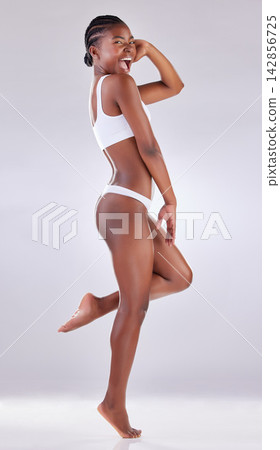 Happy woman, health and fitness in underwear for wellness, body care and balance on toes in studio. Portrait of excited African model with joy for lose weight or workout results on a white background Happy woman, health and fitness in underwear for wellness, body care and balance on toes in studio. Portrait of excited African model with joy for lose weight or workout results on a white background 142856725