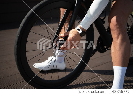 Cyclist checking road bicycle disc brake Cyclist checking road bicycle disc brake 142856772