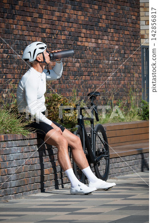 Male cyclist drinking water during break from bike ride 142856817