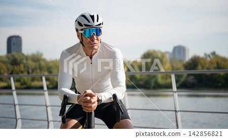 Male cyclist resting on road bike outdoors Male cyclist resting on road bike outdoors 142856821
