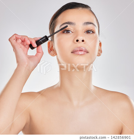 Woman, portrait and mascara makeup or eyelash cosmetics on white background, beauty or makeover. Female person, face and wand tool for application in studio or skincare, transformation or routine Woman, portrait and mascara makeup or eyelash cosmetics on white background, beauty or makeover. Female person, face and wand tool for application in studio or skincare, transformation or routine 142856901