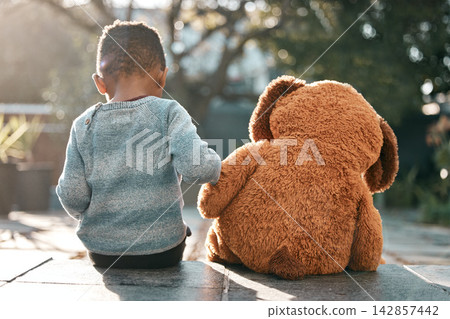 Child, teddy bear and back in backyard for fantasy, play and enjoyment in sunlight. Young boy, toy and sitting together in garden for games, imagination and development at family home in spring Child, teddy bear and back in backyard for fantasy, play and enjoyment in sunlight. Young boy, toy and sitting together in garden for games, imagination and development at family home in spring 142857442