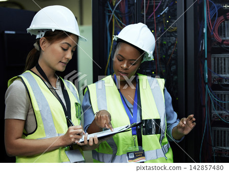 Clipboard, women and data programmer as engineer in computer center in teamwork or collaboration. Female people, pointing and tech in hardware security in server room for system update or maintenance Clipboard, women and data programmer as engineer in computer center in teamwork or collaboration. Female people, pointing and tech in hardware security in server room for system update or maintenance 142857480