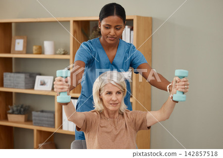 Weights, exercise and physiotherapist with senior patient in office at hospital for consultation. Physical therapy, dumbbells and healthcare worker helping elderly woman with arm rehabilitation. Weights, exercise and physiotherapist with senior patient in office at hospital for consultation. Physical therapy, dumbbells and healthcare worker helping elderly woman with arm rehabilitation. 142857518