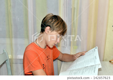 A boy is reading a book. Side view. A boy is reading a book. Side view. 142857623