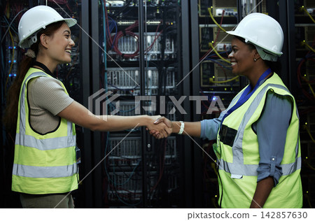Handshake, women and data programmer as engineer in computer center for teamwork or collaboration. Female people, smile and tech for hardware security in server room for system update or maintenance Handshake, women and data programmer as engineer in computer center for teamwork or collaboration. Female people, smile and tech for hardware security in server room for system update or maintenance 142857630