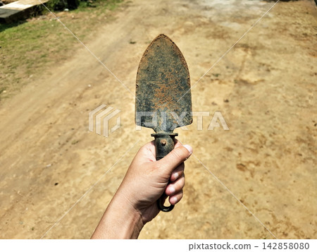 Person hand holding dirty metal hand shovel for planting. Person hand holding dirty metal hand shovel for planting. 142858080