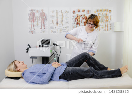 Doctor examining patient knee reflex with hammer Doctor examining patient knee reflex with hammer 142858825