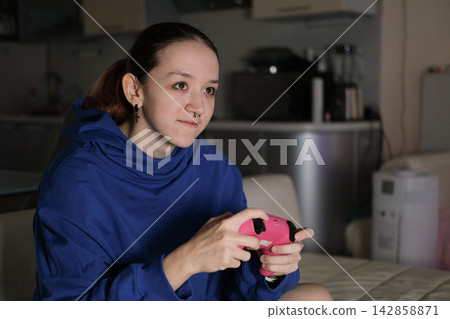 Focused teenage gamer playing alone at home reflects concentration persistence self confidence and growing independence through personal digital interests Focused teenage gamer playing alone at home reflects concentration persistence self confidence and growing independence through personal digital interests 142858871