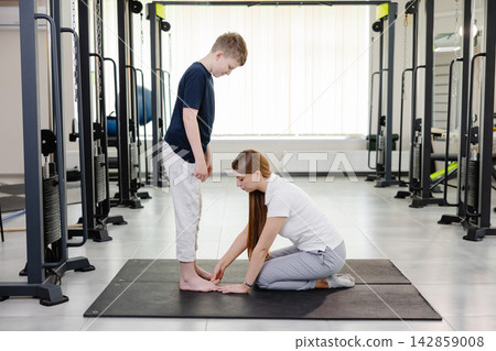 Physiotherapist examining posture of young patient in rehabilitation center Physiotherapist examining posture of young patient in rehabilitation center 142859008