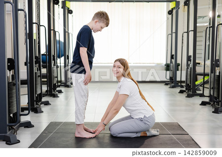 Physiotherapist examining posture of young patient in rehabilitation center 142859009