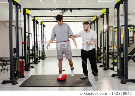 Physiotherapist assisting young man with balance training Physiotherapist assisting young man with balance training 142859043