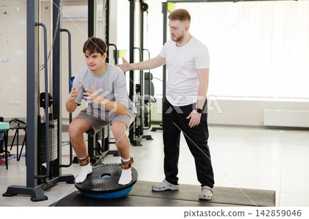 Rehabilitation training with physical therapist in gymnasium Rehabilitation training with physical therapist in gymnasium 142859046
