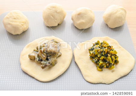 The process of making homemade oyaki: Putting the filling on top of the dough The process of making homemade oyaki: Putting the filling on top of the dough 142859091