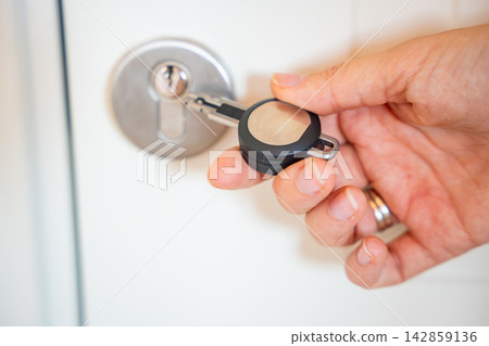 Close up view of hand using an RFID key fob to unlock an apartment door with electronic access system. Concept of keyless entry, smart security and modern access control. Close up view of hand using an RFID key fob to unlock an apartment door with electronic access system. Concept of keyless entry, smart security and modern access control. 142859136