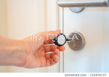 Hand using an RFID key fob to unlock an apartment door with electronic access system. Concept of keyless entry, smart security and modern access control. Hand using an RFID key fob to unlock an apartment door with electronic access system. Concept of keyless entry, smart security and modern access control. 142859137