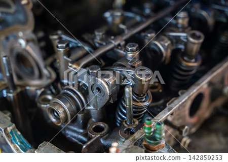 Disassembled car engine with exposed valve train and cylinder head. Internal engine components represent automotive repair, diagnostics and maintenance Disassembled car engine with exposed valve train and cylinder head. Internal engine components represent automotive repair, diagnostics and maintenance 142859253