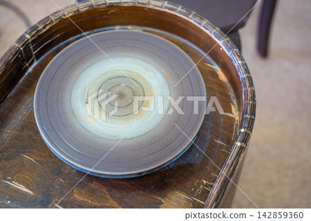 Pottery wheel prepared for shaping clay in ceramic workshop. Traditional pottery equipment represents handmade craft and ceramic production process Pottery wheel prepared for shaping clay in ceramic workshop. Traditional pottery equipment represents handmade craft and ceramic production process 142859360