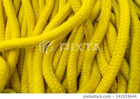 Coiled bright yellow marine rope texture in close up. Nautical safety equipment and durable braided cord background. Coiled bright yellow marine rope texture in close up. Nautical safety equipment and durable braided cord background. 142859644