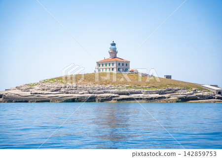 Porer Lighthouse on Porer Islet near Cape Kamenjak in Istria Croatia on the Adriatic Sea. Historic lighthouse guiding maritime navigation along the rocky coast. Porer Lighthouse on Porer Islet near Cape Kamenjak in Istria Croatia on the Adriatic Sea. Historic lighthouse guiding maritime navigation along the rocky coast. 142859753