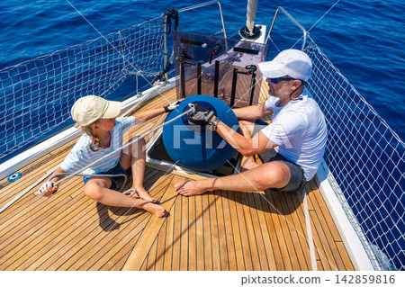 Father and daughter learning yacht maintenance together during a family sailing adventure. Building practical sailing skills, teamwork, confidence and responsibility through shared experience. Father and daughter learning yacht maintenance together during a family sailing adventure. Building practical sailing skills, teamwork, confidence and responsibility through shared experience. 142859816