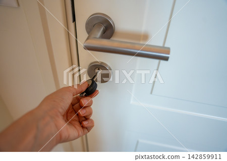 Hand using an RFID key fob to unlock an apartment door with electronic access system. Concept of keyless entry, smart security and modern access control. Hand using an RFID key fob to unlock an apartment door with electronic access system. Concept of keyless entry, smart security and modern access control. 142859911