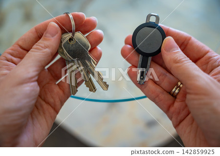 Hands holding traditional metal keys and an RFID key fob together. Concept of transition from mechanical locks to electronic access control and smart security technology Hands holding traditional metal keys and an RFID key fob together. Concept of transition from mechanical locks to electronic access control and smart security technology 142859925