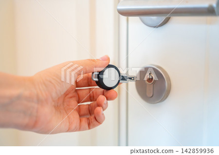 Hand using an RFID key fob to unlock an apartment door with electronic access system. Concept of keyless entry, smart security and modern access control. Hand using an RFID key fob to unlock an apartment door with electronic access system. Concept of keyless entry, smart security and modern access control. 142859936