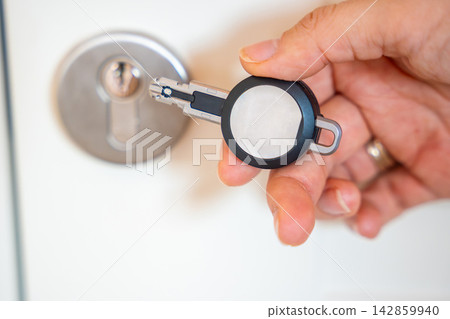 Close up view of hand using an RFID key fob to unlock an apartment door with electronic access system. Concept of keyless entry, smart security and modern access control. 142859940