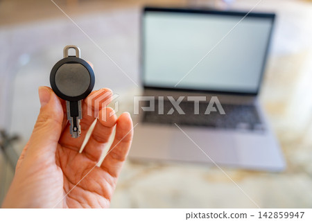 Hand holding an RFID key fob in front of a computer monitor. Concept of programming electronic access credentials, smart security systems and digital access management. Hand holding an RFID key fob in front of a computer monitor. Concept of programming electronic access credentials, smart security systems and digital access management. 142859947