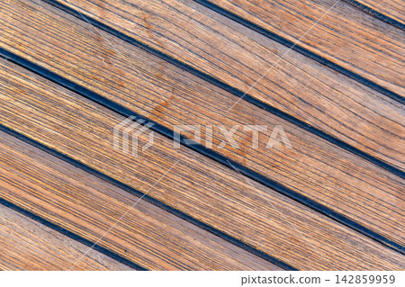 Close up of teak wooden decking on a sailing yacht creating a clean nautical texture and seamless background. Concept of marine design, luxury boating, craftsmanship and premium natural materials. Close up of teak wooden decking on a sailing yacht creating a clean nautical texture and seamless background. Concept of marine design, luxury boating, craftsmanship and premium natural materials. 142859959