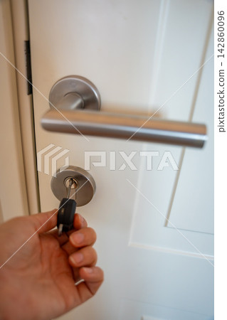 Hand using an RFID key fob to unlock an apartment door with electronic access system. Concept of keyless entry, smart security and modern access control. Hand using an RFID key fob to unlock an apartment door with electronic access system. Concept of keyless entry, smart security and modern access control. 142860096